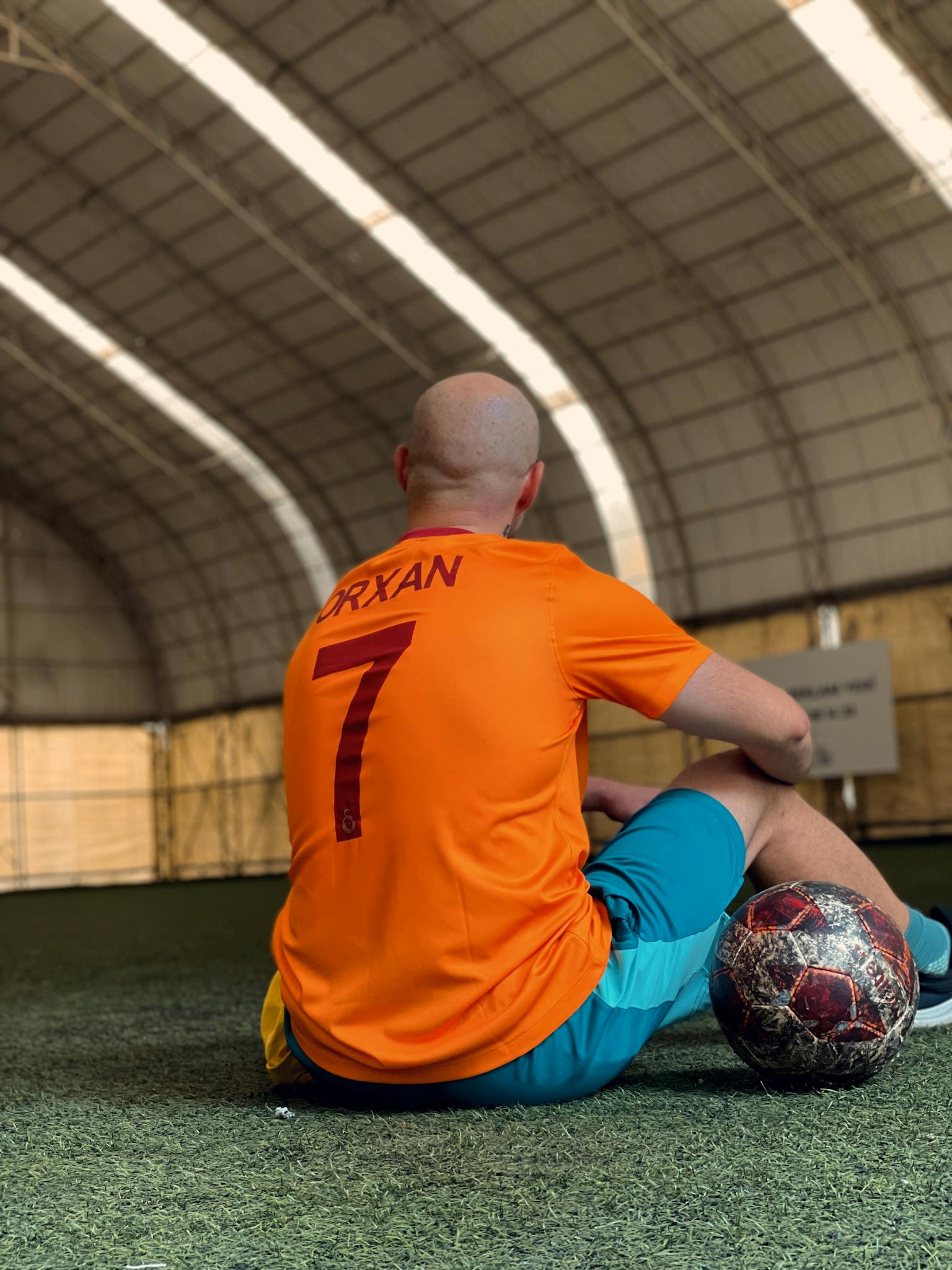 Man in sportswear sitting with handball in Baku sports hall.